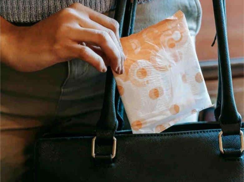 A woman placing a sanitary napkin inside a bag