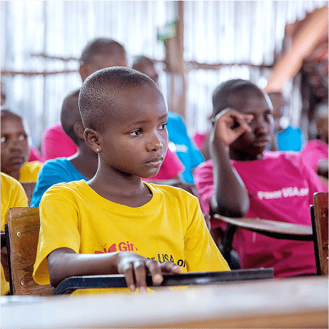 A child sitting in front of a desk wearing Girl Power USA t-shirt