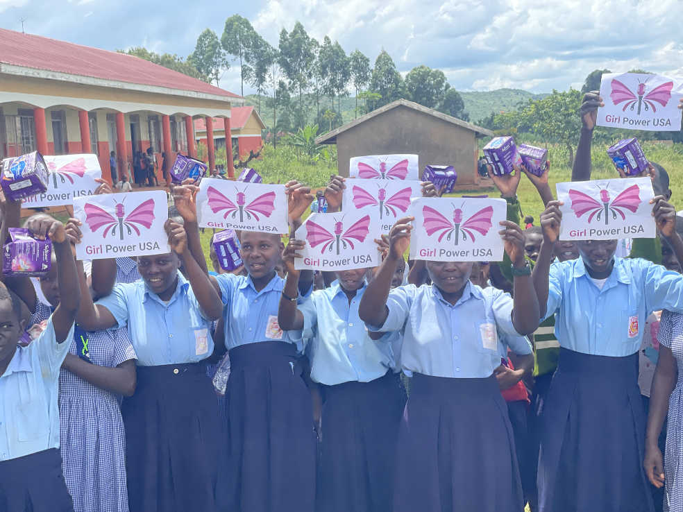 School girl carrying pads and Girl Power USA posters after a period education session