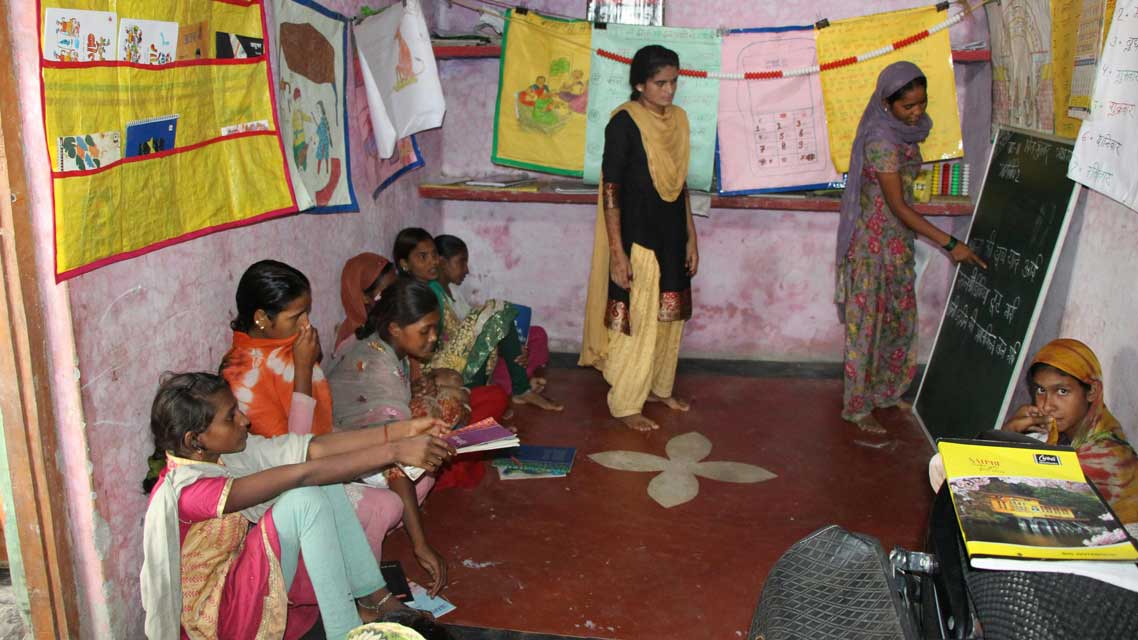 Girls attending class with two teachers standing - Education in India