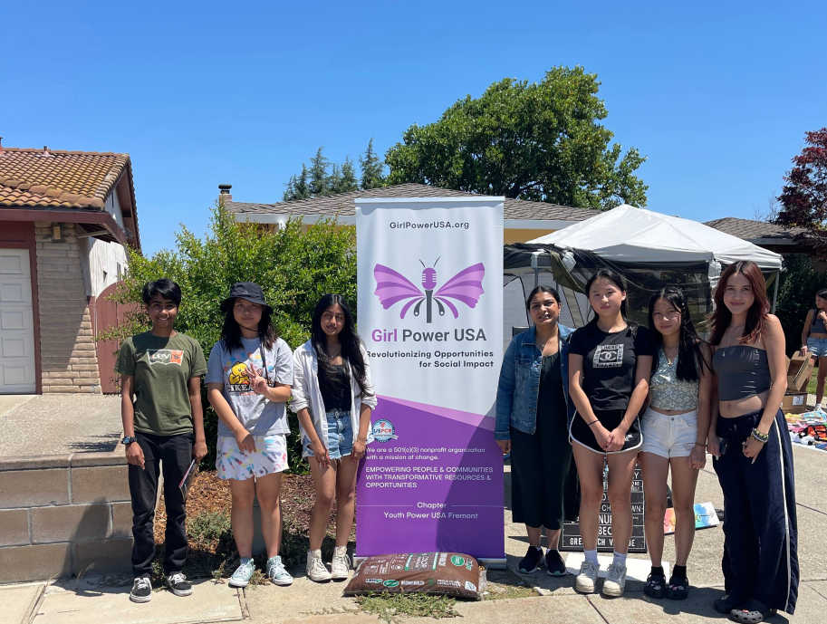 Girl-Power-USA-volunteers-standing-near-a-social-impact-stand
