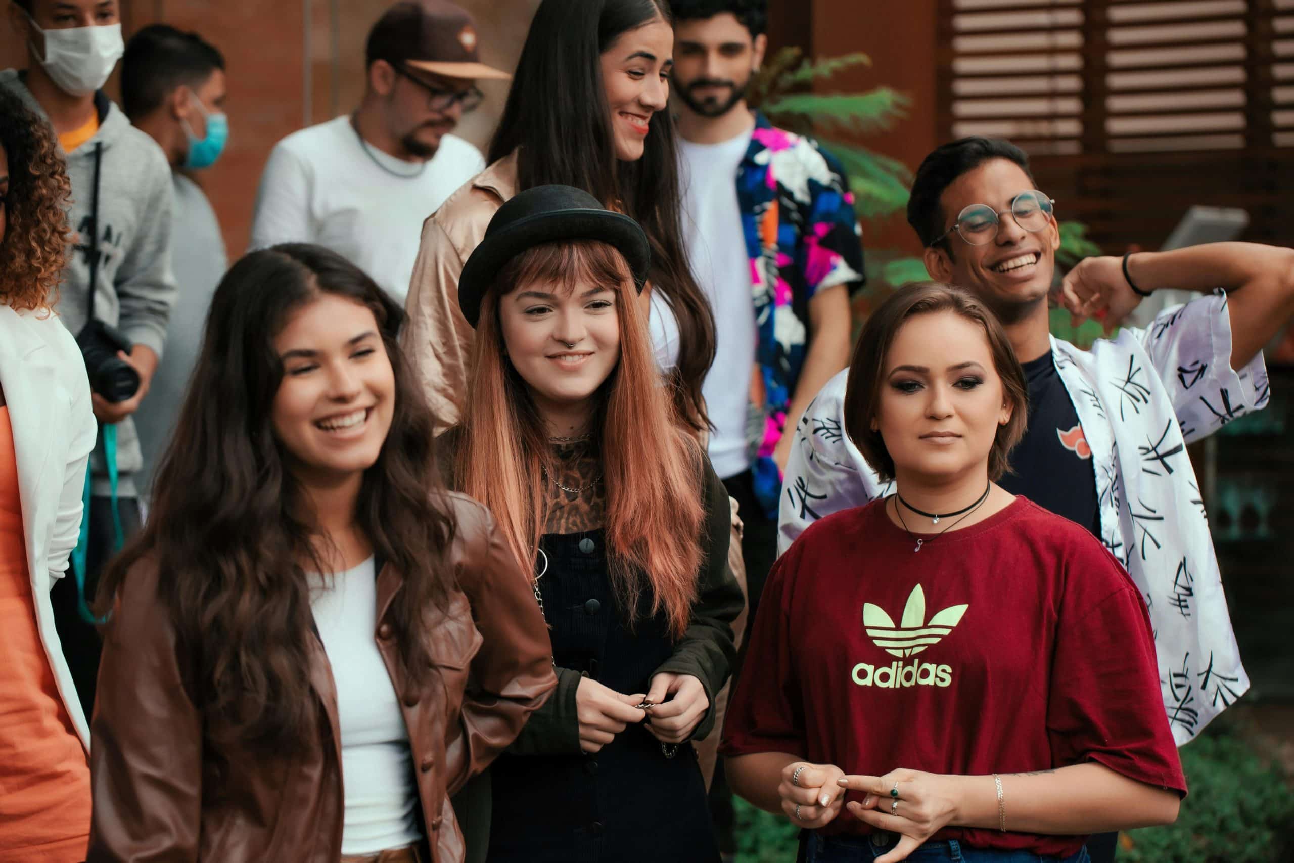 A lively group of young adults enjoying a casual outdoor gathering, smiling and socializing.