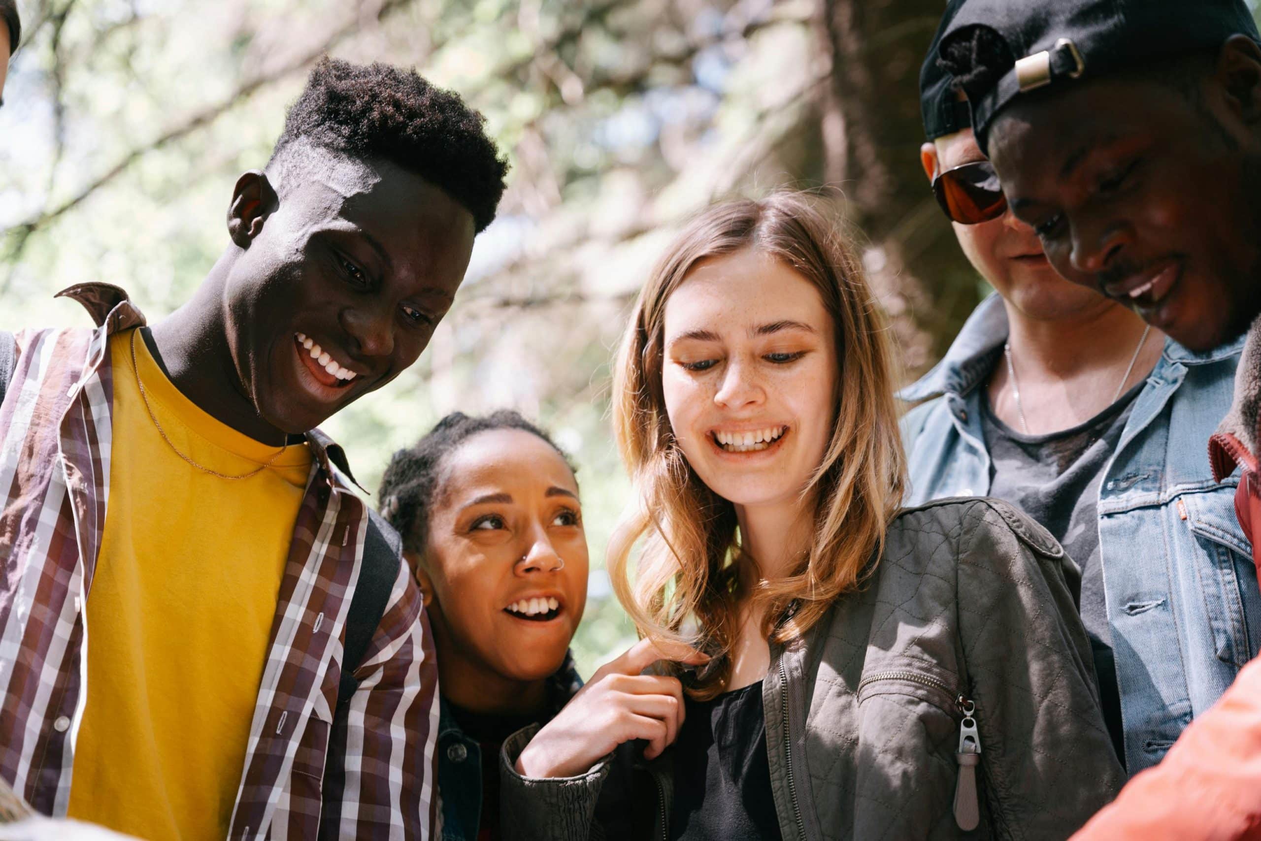 A lively group of young adults enjoying a casual outdoor gathering, smiling and socializing.