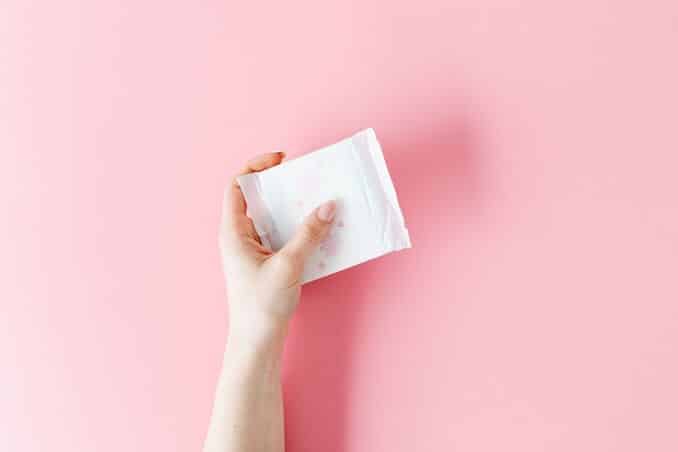 Close-up-image-of-a-hand-holding-a-sanitary-napkin-on-a-pink-background